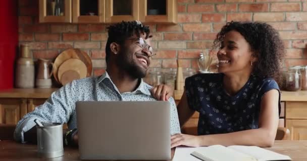 Счастливая молодая африканская супружеская пара с ноутбуком на кухне — стоковое видео