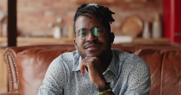 Portret lachend knappe Afro-Amerikaanse mannelijke hipster zittend op de bank — Stockvideo