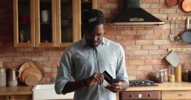 Siyah erkek akıllı telefon banka kartıyla internetten gıda siparişi veriyor.
