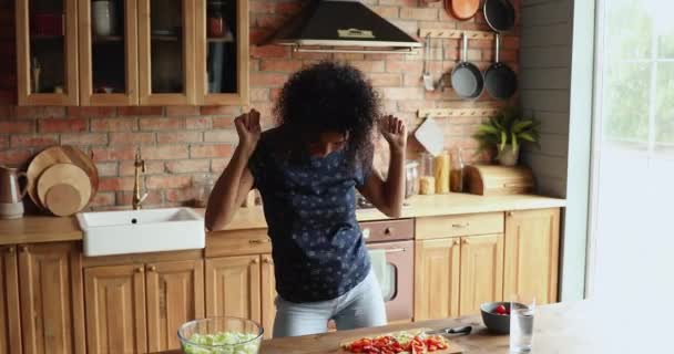 Glad aktiv tusenårig svart hemmafru dans i köket njuta av matlagning — Stockvideo