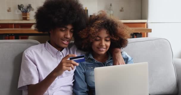 Africano pareja adolescente comprar uso en línea portátil y tarjeta de débito — Vídeos de Stock