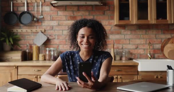 Sonriente joven mujer africana mantener conversación de videollamada utilizando el teléfono inteligente — Vídeos de Stock