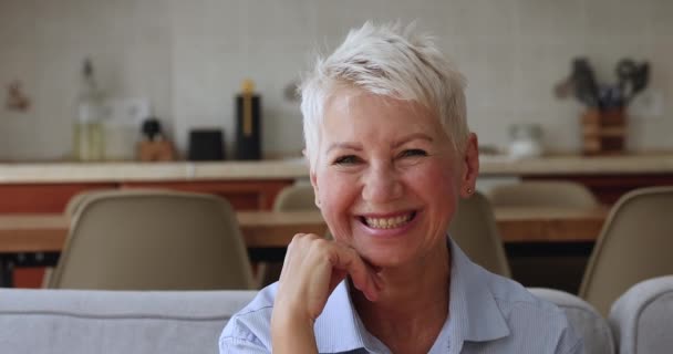 Porträtt glad äldre kvinna sitta på soffan posera vid kameran — Stockvideo
