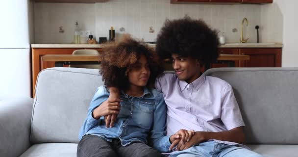 Adorável casal adolescente Africano sentar no sofá sorriso desfrutar de conversa — Vídeo de Stock