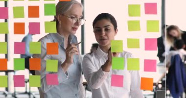 Olgun kadın akıl hocası genç Hintli kadın stajyer Kanban tahtası kullanıyor.