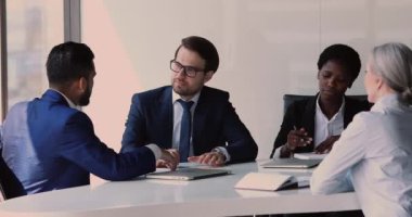 Çeşitli iş ortakları konferans masasında oturup anlaşma pazarlığını tartışır.