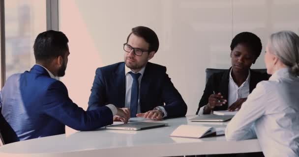 Diverse zakenpartners zitten rond conferentietafel bespreken deal koopje — Stockvideo