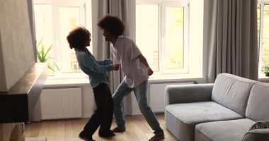 Güzel Afrikalı kız arkadaş, erkek arkadaşıyla oturma odasında dans ediyor.