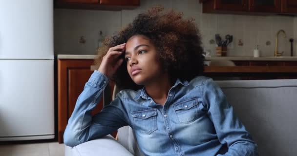 Afrikalı genç kız üzgün düşüncelere dalmış koltukta oturuyor. — Stok video