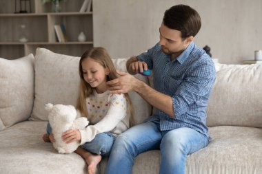 Sevgi dolu baba, uzun saçlarını tarıyor. Mutlu tatlı kız.