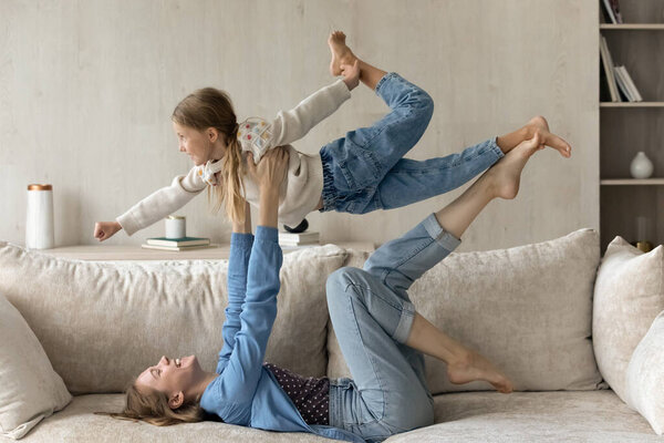 Joyful happy mom holding daughter kid up in air