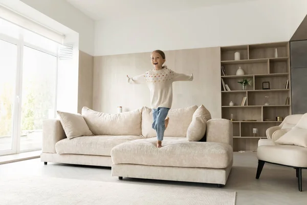 Excited cheerful girl kid jumping on comfortable couch — Stock Photo, Image