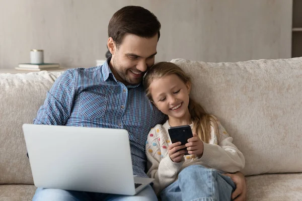 Щасливий тато і дочка дитина використовує смартфон і ноутбук — стокове фото