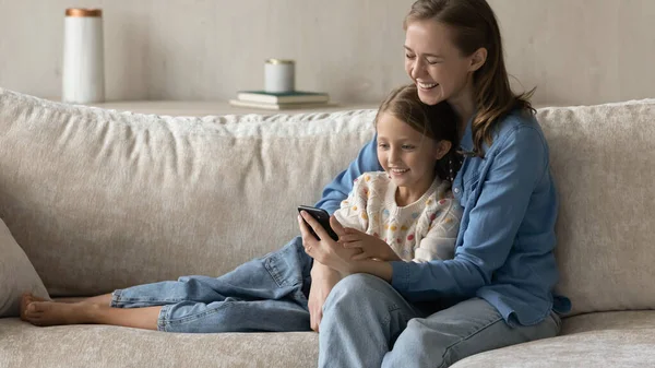 Счастливые мама и ребенок, используя онлайн приложение электронной коммерции на смартфоне — стоковое фото