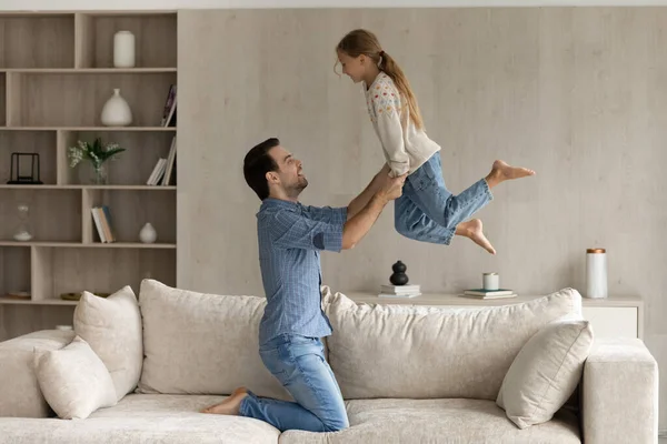 Excited happy strong dad lifting cheerful daughter — Stock Photo, Image