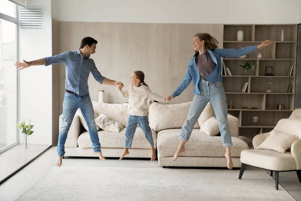 Happy overjoyed parents and daughter kid holding hands and jumping