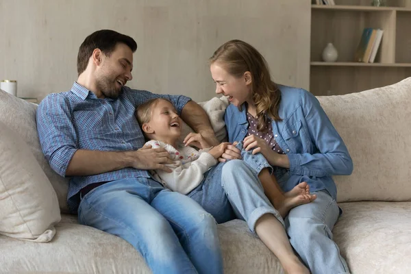 Mutlu, genç ebeveynler sarılıyor, gıdıklıyor heyecanlı, neşeli, tatlı kız çocuğu