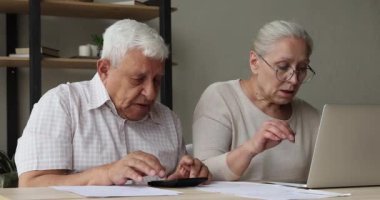 Yaşlı çift e-bankacılık başvurusu üzerinden fatura ödeyerek dizüstü bilgisayar kullanıyor.