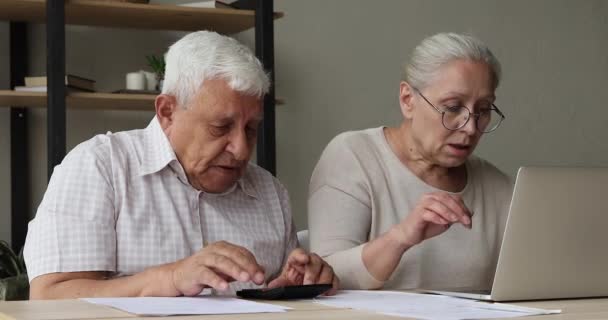 Пожилая пара с помощью ноутбука оплачивает счета через приложение электронного банкинга — стоковое видео