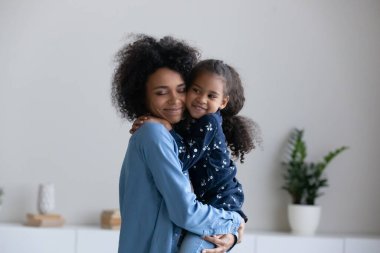 Küçük çocuğu kucağında tutan mutlu Afrikalı genç Amerikalı anne..