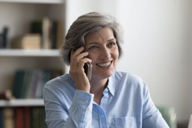 Gülümseyen orta yaşlı güzel bir kadın telefon konuşması yapıyor..