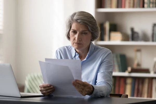 Сосредоточенная деловая женщина средних лет на финансовых документах. — стоковое фото