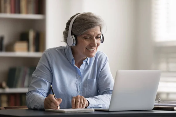 Счастливая женщина средних лет учится на онлайн лекции. — стоковое фото