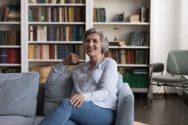 Gülümseyen yaşlı bir kadının portresi rahat koltukta dinleniyor..