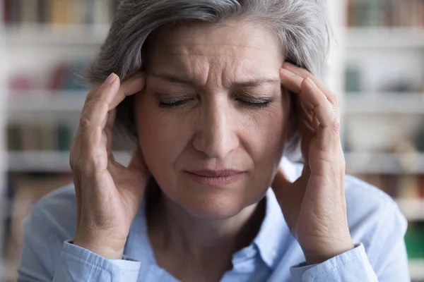 Zestresowana nieszczęśliwa starsza kobieta z silnym bólem głowy. — Zdjęcie stockowe
