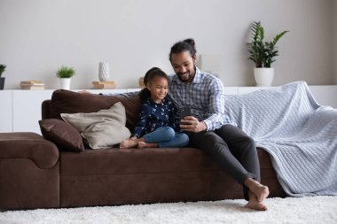Kızıyla cep telefonu kullanan mutlu Afrikalı genç bir Amerikalı..