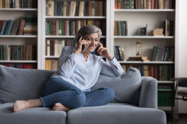 Mutlu, orta yaşlı bir kadın telefon görüşmesi yapıyor..