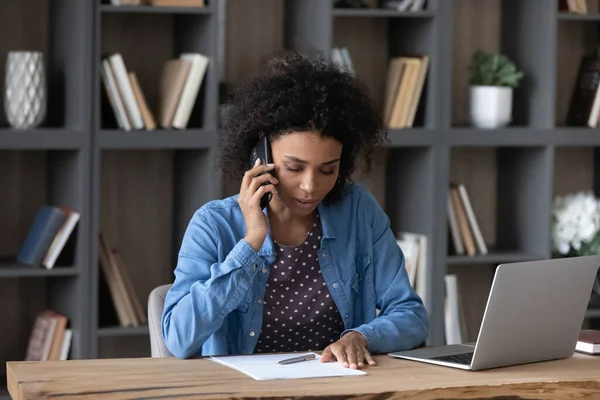 Koncentrerad ung afroamerikansk kvinna multitasking i modernt kontor. — Stockfoto