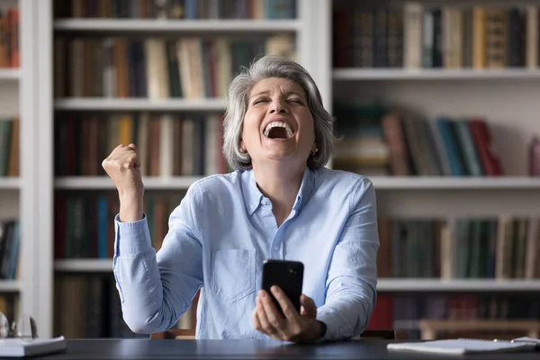 Alegre mujer de mediana edad celebrando la lotería en línea ganar. — Foto de Stock