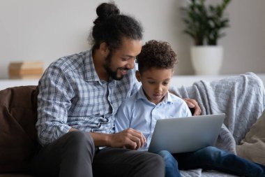 Mutlu genç Afrikalı Amerikalı baba, küçük çocukla bilgisayar kullanıyor..