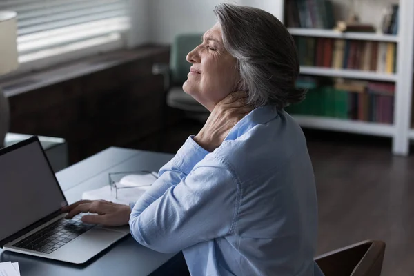 Stressed mature businesswoman suffering from stiff neck. — Stock Photo, Image