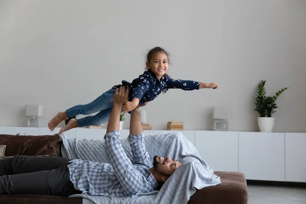Розслаблений афроамериканець піднімається в повітрі смішна дочка. — стокове фото