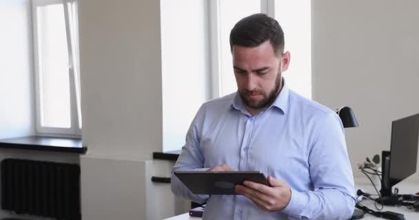 Усміхнений багаторічний бізнесмен працює на цифровому планшеті, стоячи на робочому місці — стокове відео