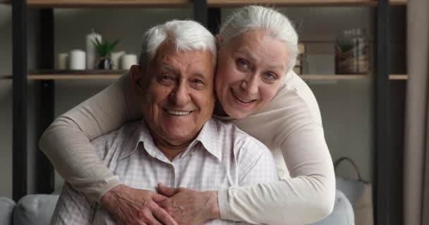 Ältere Frau und Mann umarmen sich lächelnd und blicken in die Kamera — Stockvideo