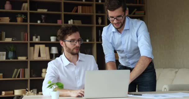 Młody mężczyzna pracujący na laptopie poprosić brata bliźniaka o pomoc — Wideo stockowe