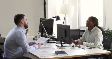 Çok ırklı erkek iş arkadaşları ortak masada oturup ortak görevi tartışırlar.