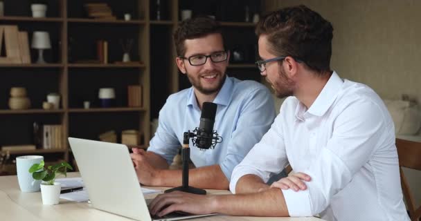 Два брата близнеца записывают веб-подкаст с помощью профессионального ноутбука микрофона — стоковое видео