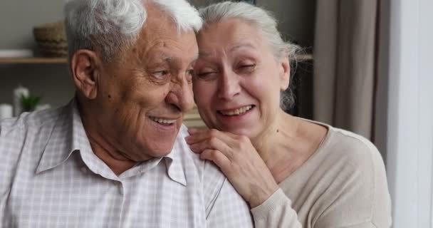 Закройте веселые пожилые супруги разговаривая смеясь обнимаясь внутри — стоковое видео
