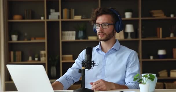 Hombre joven en auriculares grabar podcast en el ordenador portátil utilizando el micrófono — Vídeo de stock