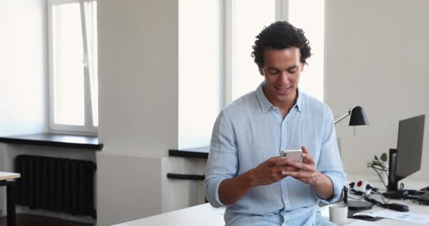 Fešák mladý podnikatel stojící v moderních kancelářských prostorech používat smartphone — Stock video