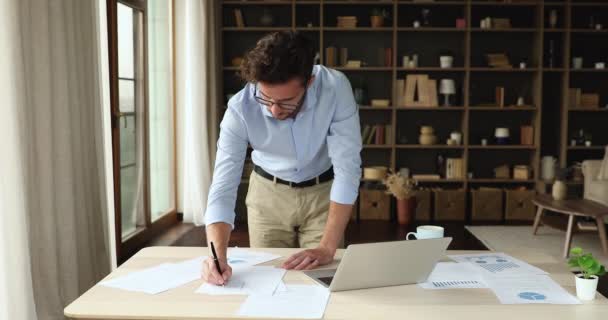 초점을 맞춘 젊은 남자는 가정 사무실에서 일하는 정확 한 자료를 분석 한다 — 비디오