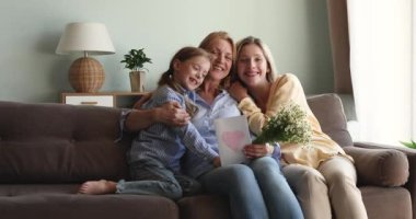 Nesiller boyu kadınlar kanepeye kartpostal ve çiçeklerle oturur.