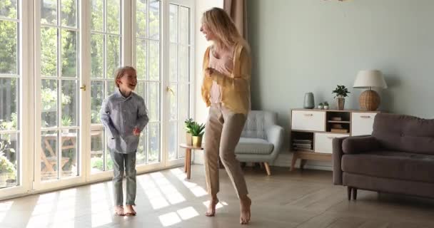 Mujer feliz su hija escuchar música bailando en la sala de estar — Vídeos de Stock