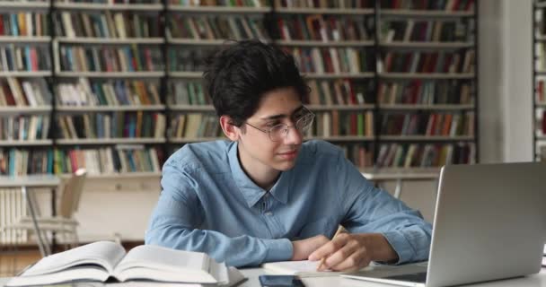 Intelligenter Schüler mit Laptop in der Hochschulbibliothek — Stockvideo