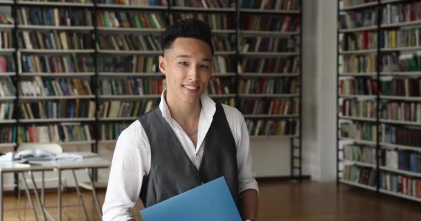 Snímek hlavy portrét úspěšný pilný asijský student pózování v knihovně — Stock video