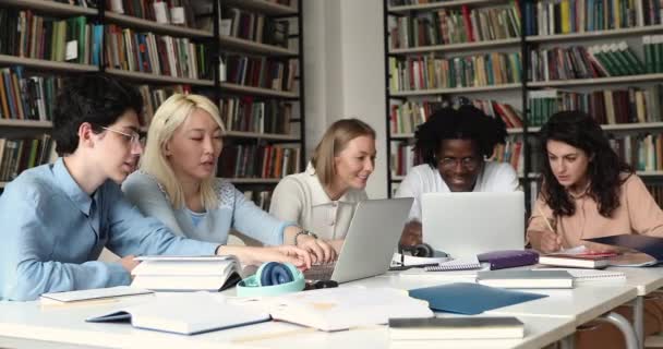 Jovens estudantes trabalham em grupo em pesquisa usando fontes de papel para laptops — Vídeo de Stock